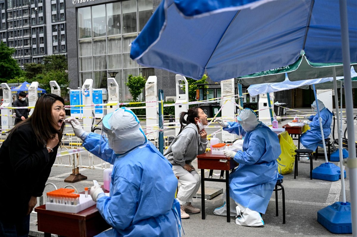 <i>Jade Gao/AFP/Getty Images</i><br/>Health workers take swab samples to be tested for Covid-19 at a makeshift testing site along a street in Beijing on May 11.