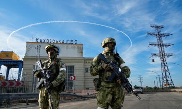 Russian troops guard an entrance of a Kakhovka power plant in southern Ukraine