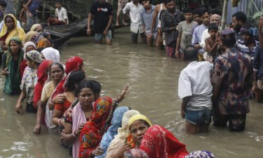 Flood affected people queue in knee-deep flood waters to collect food relief following heavy monsoon rainfalls in Sunamganj district