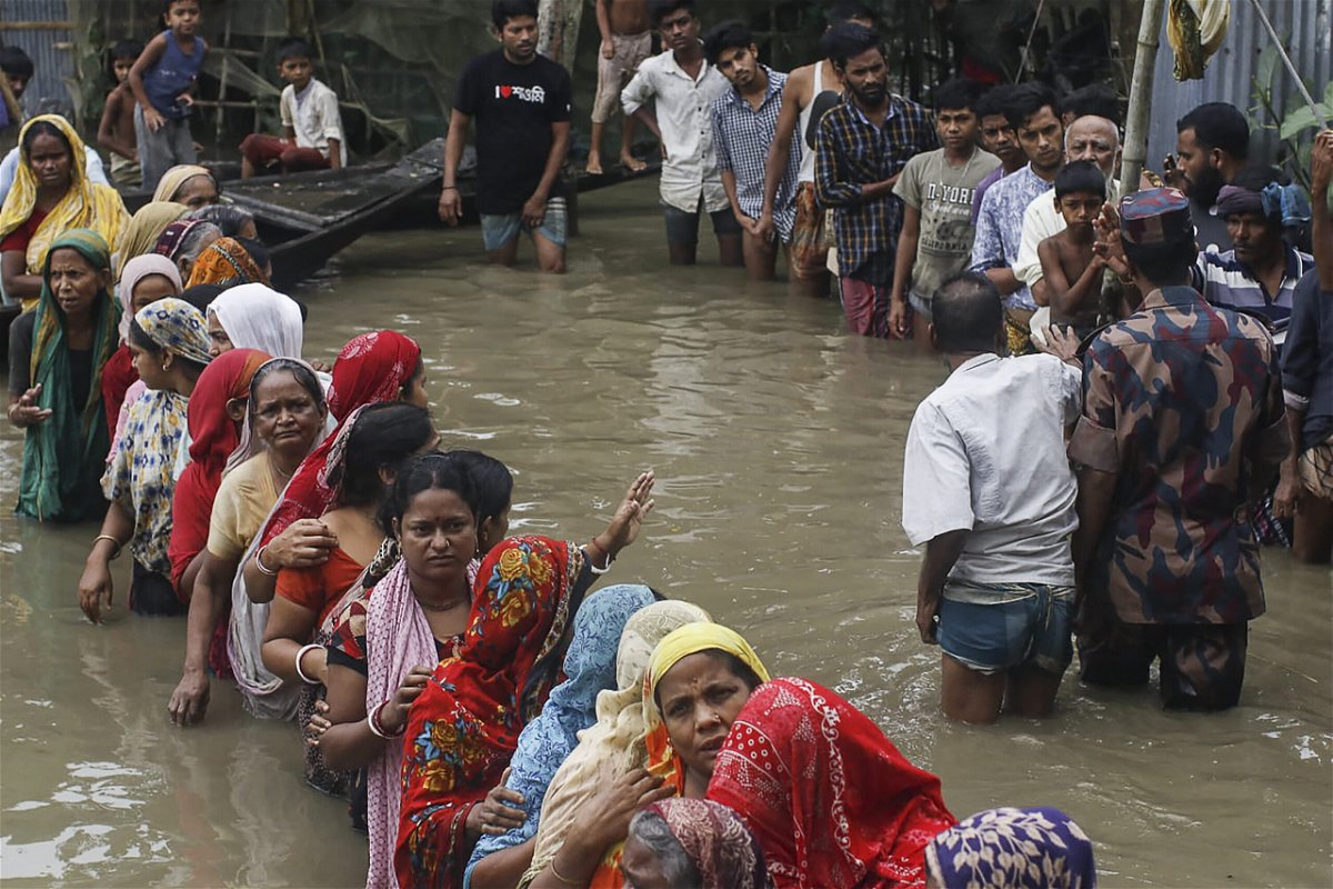 <i>Md Abu Sufian Jewel/AFP/Getty Images</i><br/>Flood affected people queue in knee-deep flood waters to collect food relief following heavy monsoon rainfalls in Sunamganj district
