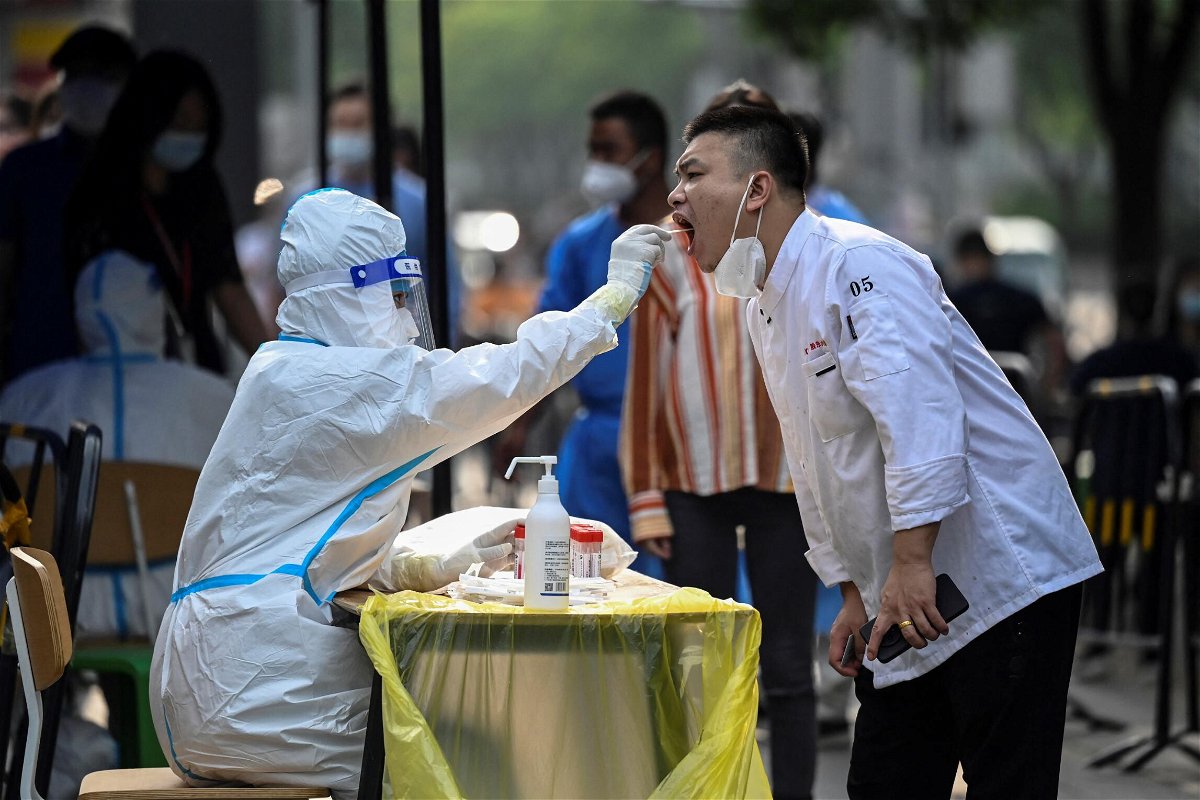 <i>Jade Gao/AFP/Getty Images</i><br/>A health worker takes a swab sample from a man at a makeshift testing site outside a shopping mall in Beijing on June 15.