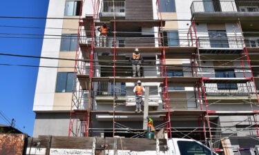 Construction workers pass planks of wood during the construction of new apartments in Monterey Park