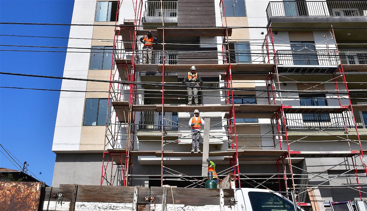 <i>Frederic J. Brown/AFP/Getty Images</i><br/>Construction workers pass planks of wood during the construction of new apartments in Monterey Park