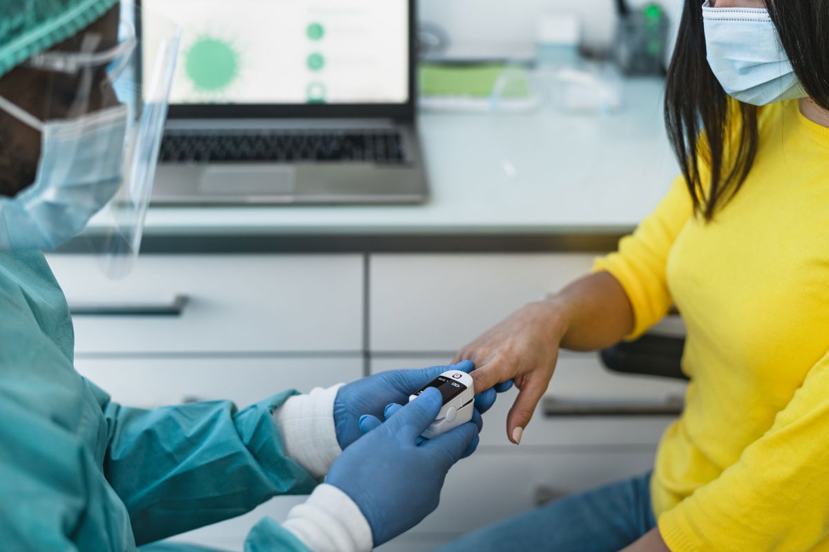 <i>Alessandro Biascioli/Adobe Stock</i><br/>A medical worker examines a female patient with an oximeter device during the coronavirus outbreak.