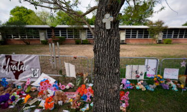 A cross hangs on a tree at Robb Elementary School on June 3