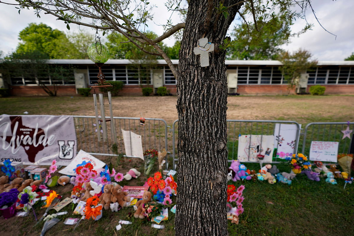<i>Eric Gay/AP</i><br/>A cross hangs on a tree at Robb Elementary School on June 3