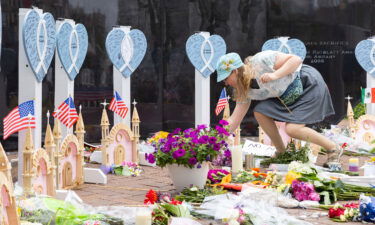 Highland Park resident Emily Mace places flowers at the memorials for the 7 killed in the 4th of July shooting in Highland Park Illinois. Mace was at the parade with her children