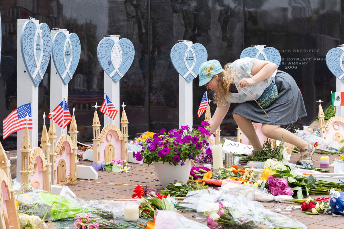 <i>Kristan Lieb for CNN</i><br/>Highland Park resident Emily Mace places flowers at the memorials for the 7 killed in the 4th of July shooting in Highland Park Illinois. Mace was at the parade with her children