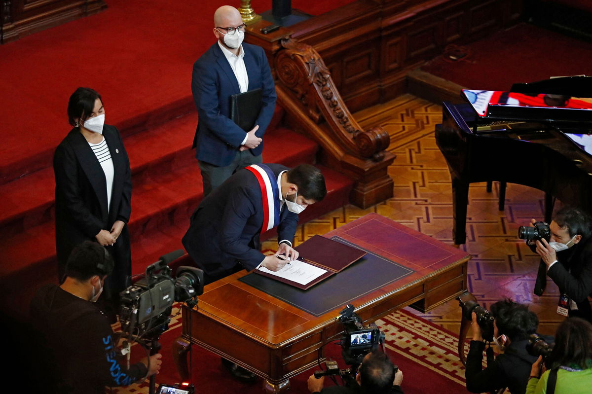 <i>Javier Torres/AFP/Getty Images</i><br/>President Boric signing the proposal.