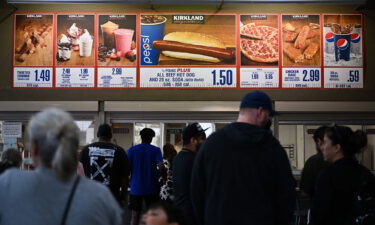 Customers wait in line to order below signage for the Costco Kirkland Signature $1.50 hot dog and soda combo.