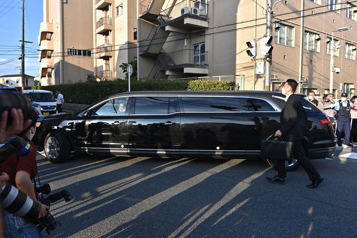 <i>Philip Fong/AFP/Getty Images</i><br/>The car believed to carry the body of Japan's late former prime minister Shinzo Abe passes by policemen and media outside the Nara Medical University Hospital in Kashihara