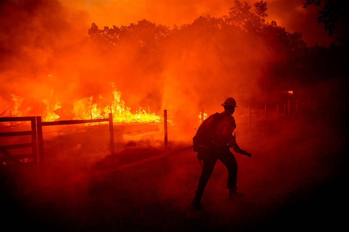 <i>Noah Berger/AP</i><br/>A firefighter runs to extinguish flames from the Oak Fire in Mariposa County on Friday.