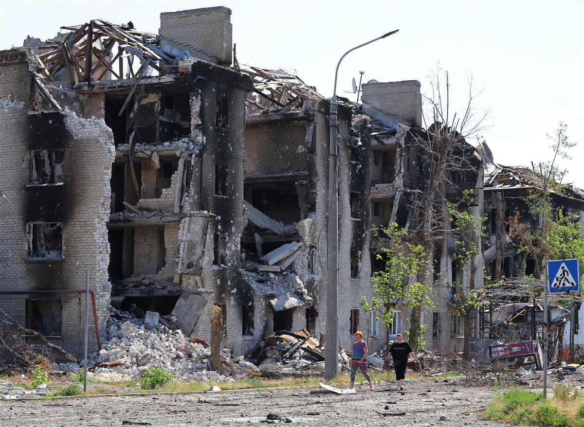 <i>ALEXANDER ERMOCHENKO/X03560/REUTERS</i><br/>Local residents walk past apartment buildings destroyed during Ukraine-Russia conflict in the city of Sievierodonetsk in the Luhansk Region