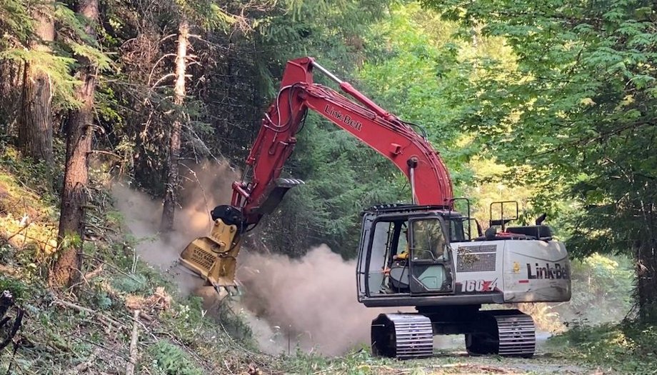 A heavy equipment operator utilizes a masticator head on an excavator to grind fuels and widen the fuel break along the Black Creek Road (FS Road 2421). This road will serve as the primary containment line as the fire backs down the Koch Mountain Ridge