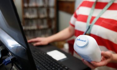 Johnson & Johnson is abandoning talc-based baby powder in 2023 and instead will make it with cornstarch. A pharmacy cashier holds a bottle of Johnson & Johnson's baby powder in Salt Lake City in February 2021.