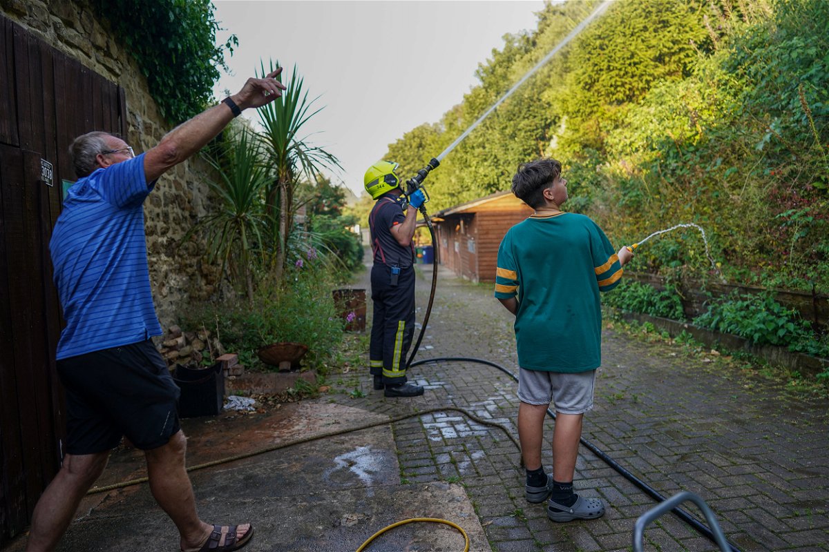 <i>Ian Forsyth/Getty Images</i><br/>Local residents use garden hoses to assist fire crews tackle a crop fire that swept over farmland and threatened local homes on August 11
