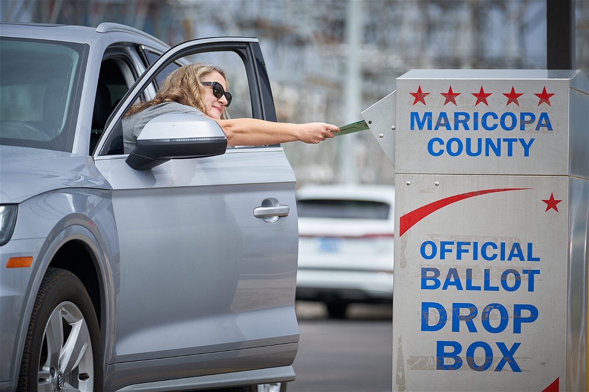 <i>Alex Gould/The Republic/USA Today Network/Imagn</i><br/>Shana Hofberger leans out of her car door to place her ballot in the ballot drop box outside the Maricopa County Tabulation and Elections Center in Phoenix for Arizona's August 2
