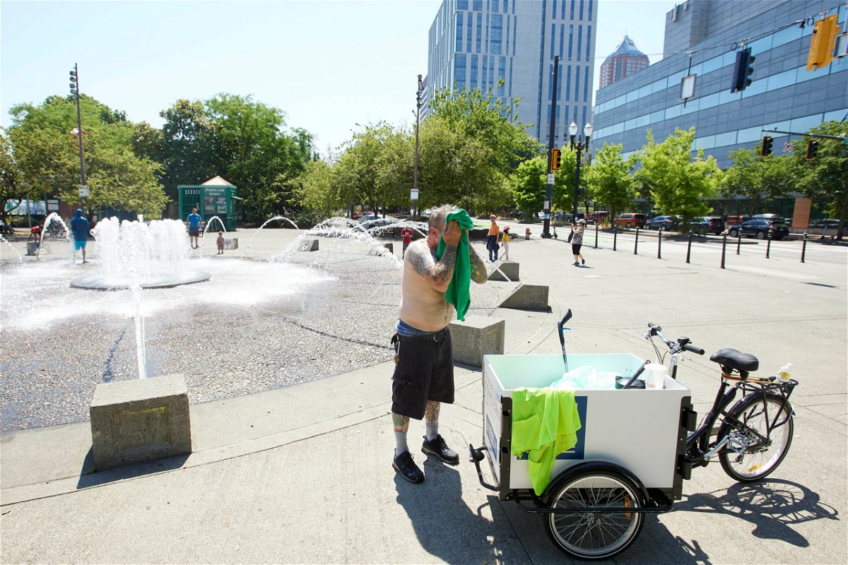 <i>Craig Mitchelldyer/AP</i><br/>Matthew Carr dries himself after cooling off in the Salmon Street Springs fountain before returning to work cleaning up trash on his bicycle in Portland