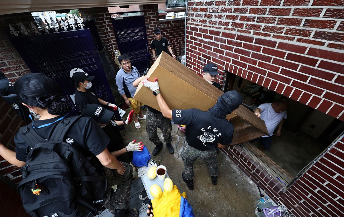 <i>Kim In-chul/AP</i><br/>Soldiers carry debris out from a flooded house in Seoul