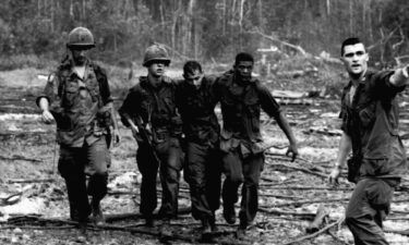 A battle weary soldier from the 173rd Airborne Division is helped across a wasteland in War Zone D