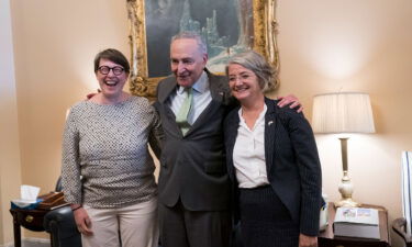 Senate Majority Leader Chuck Schumer is flanked by Paivi Nevala
