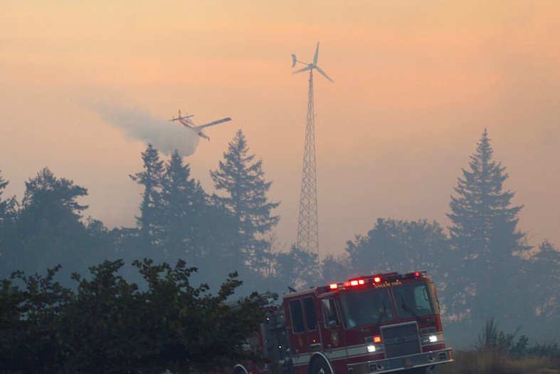 Firefighters use aircraft to battle a wildfire south of Salem, Ore., on Friday, Sept. 9, 2022. Oregon utilities shut down power to tens of thousands of customers on Friday as dry easterly winds swept into the region in the hopes that it would lessen the risk of wildfires in extremely dry and hot conditions