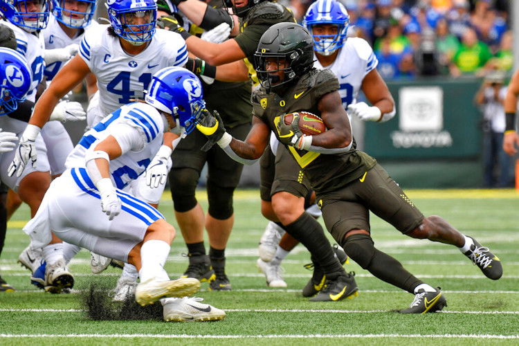 Oregon running back Mar'Keise Irving makes a cut as he rushes against BYU defensive back Ammon Hannemann and linebacker Keenan Pili during the first half of Saturday's football contest at Autzen Stadium in Eugene