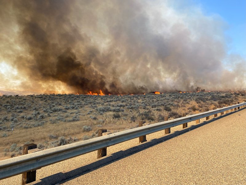 Flames from a wildfire that shut long stretches of Interstate 84 Thursday afternoon