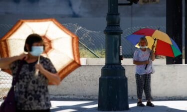 People walk with umbrellas for shade in Los Angeles on September 1.