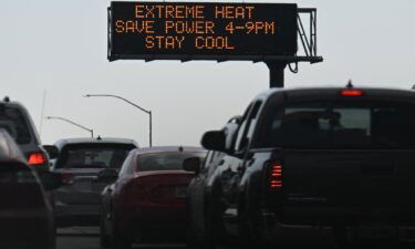 Vehicles drive past a sign on the 110 Freeway warning of extreme heat and urging energy conservation during a heat wave in downtown Los Angeles