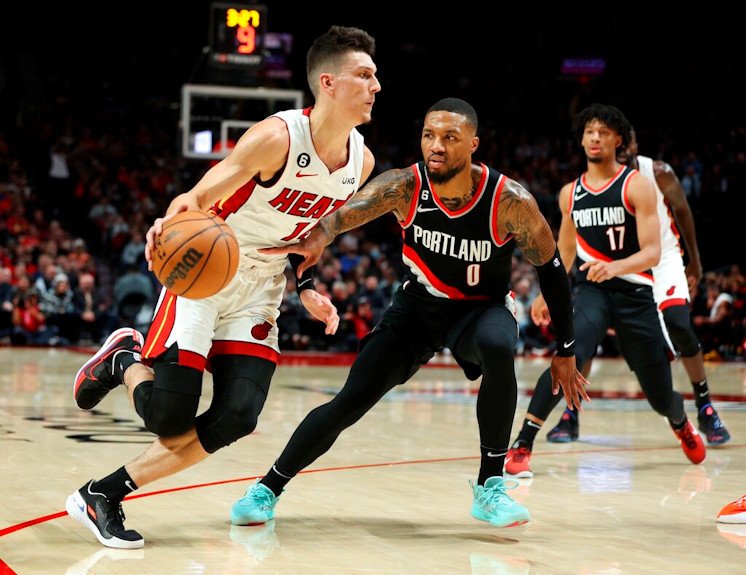 Miami Heat guard Tyler Herro, left, drives against the defense of Portland Trail Blazers guard Damian Lillard, right, during the first half of  Wednesday night's NBA contest