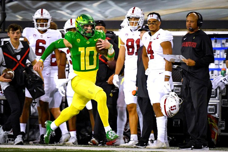 regon quarterback Bo Nix (10) runs past Stanford coach David Shaw, right, on a long gain during the first half of Saturday night's game in Eugene