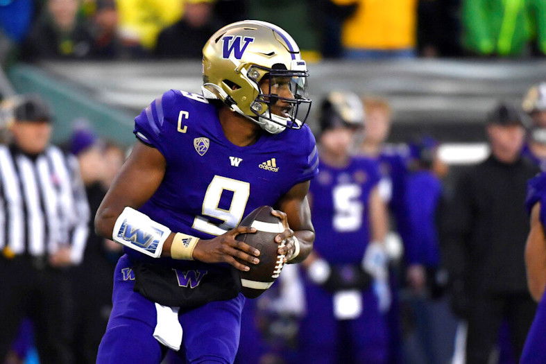Washington quarterback Michael Penix Jr. (9) rolls away from Oregon defenders and looks for a receiver during the first half  of Saturday's contest in Eugene