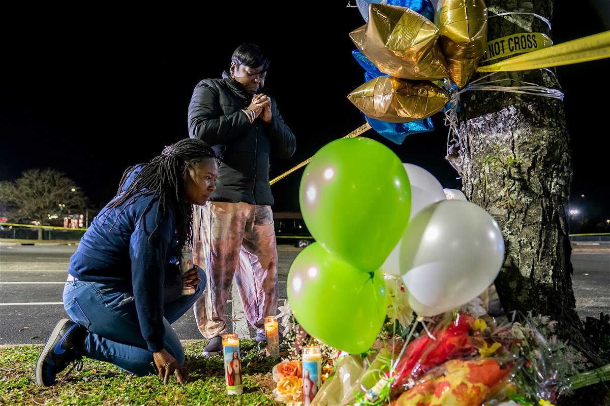 <i>Nathan Howard/Getty Images</i><br/>Lashana Hicks (left) joins other mourners Wednesday at a memorial for those killed in a mass shooting at a Walmart Supercenter in Chesapeake