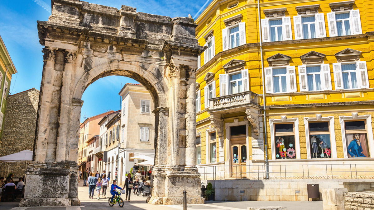 <i>A.Jedynak/Adobe Stock</i><br/>An ancient Roman arch stands in a sunny square in Pula