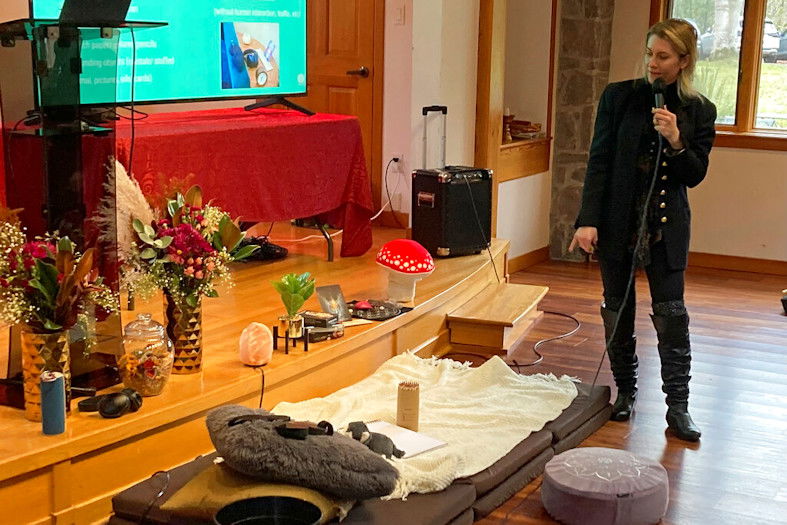 Gina Gratza, a trainer for students learning how to become psilocybin facilitators, shows the items that she would have at a dosing session, including mats, a pillow, a purge bucket, a sketch pad with colored pencils and tissues during a class near Damascus