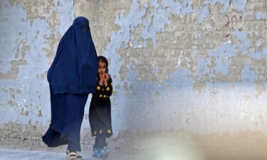 A burqa-clad woman walks with a girl along a street in Kabul on May 7. The Taliban imposed some of the harshest restrictions on Afghanistan's women since they seized power