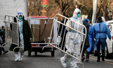 Health workers carry barricades inside a residential community that reopened following a Covid-19 lockdown in Beijing on December 9
