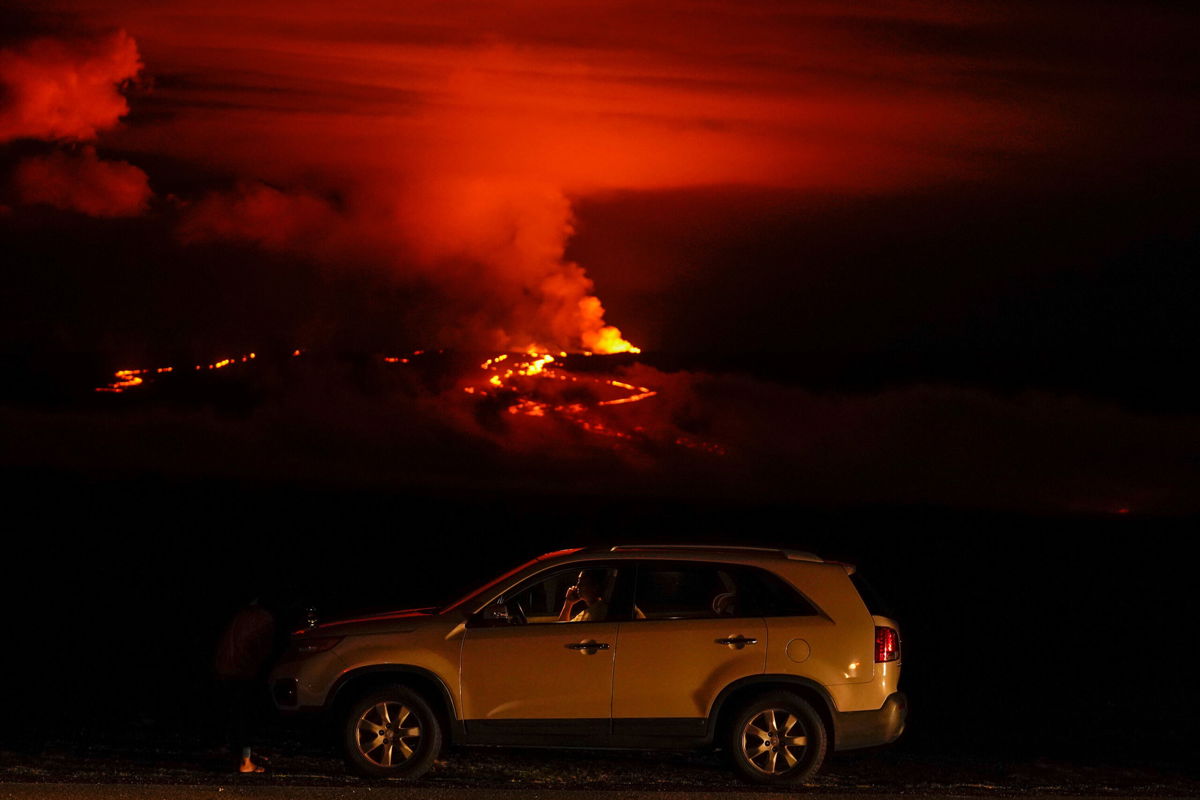 <i>Gregory Bull/AP</i><br/>A man talks on a phone in his car alongside Saddle Road as the Mauna Loa volcano erupts near Hilo