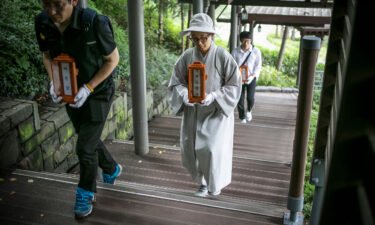 Staff and a volunteer Buddhist nun of a nonprofit organization carry the name tablets of people who died "lonely deaths" at a crematorium on June 16