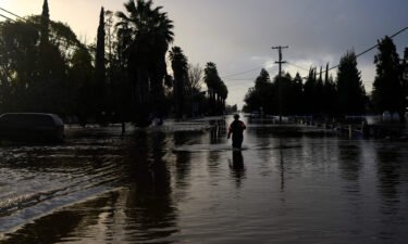 A San Diego firefighter wades through floodwaters in Merced