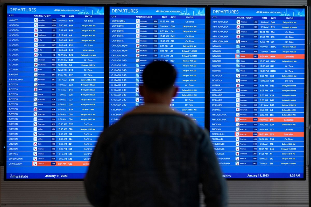 <i>Patrick Semansky/AP</i><br/>A traveler looks at a flight board with delays and cancellations at Ronald Reagan Washington National Airport in Arlington