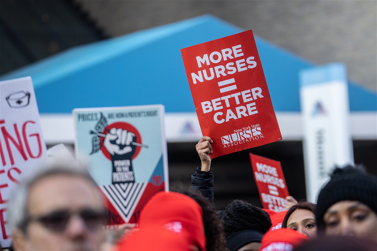 <i>Jeenah Moon/Bloomberg/Getty Images</i><br/>Nurses and healthcare workers hold signs during a strike at Mount Sinai Hospital in New York on January 9.
