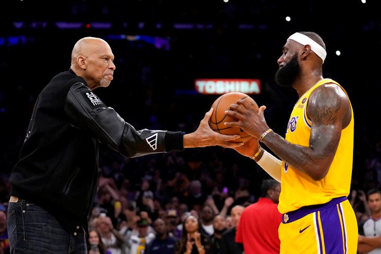 Kareem Abdul-Jabbar, hands the ball to Los Angeles Lakers forward LeBron James after passing Abdul-Jabbar to become the NBA's all-time leading scorer during the second half of a game against the Oklahoma City Thunder Tuesday night in Los Angeles