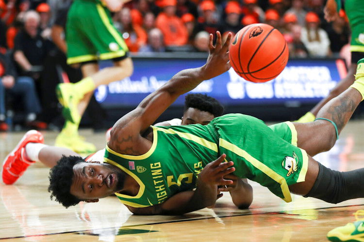 Oregon guard Jermaine Couisnard (5) passes the ball away from Oregon State center KC Ibekwe, back, during the first half of Saturday's game in Corvallis