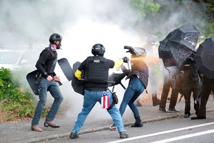 Members of the far-right group Proud Boys and anti-fascist protesters spray bear mace at each other during clashes between the politically opposed groups in Portland, Ore., Aug. 22, 2021. 
