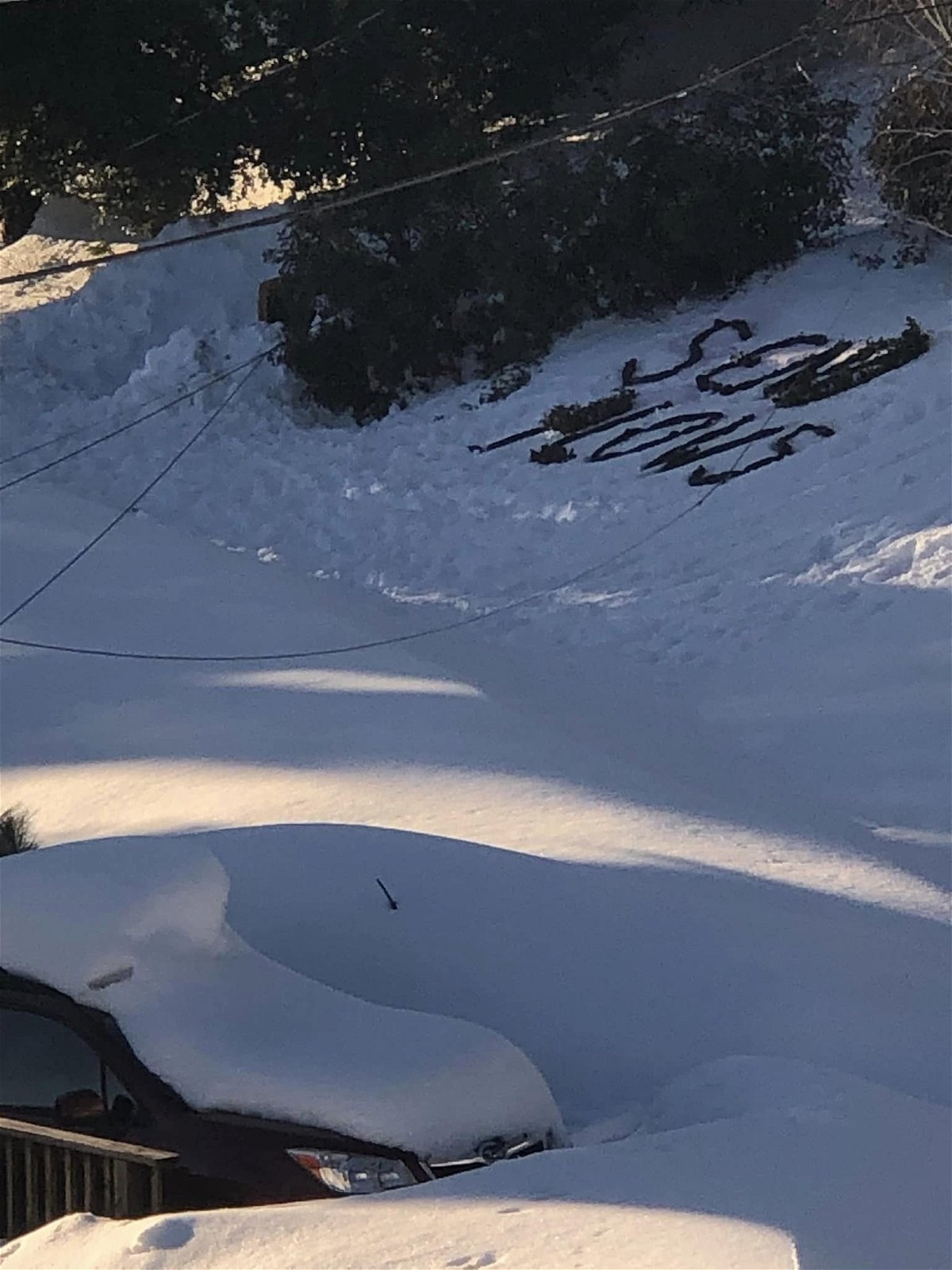 <i>Krissy Marcum</i><br/>Krissy Marcum shared video with CNN that shows “SEND PLOWS” written out in black trash bags on top of a shady patch of snow as helicopters circle the area above.