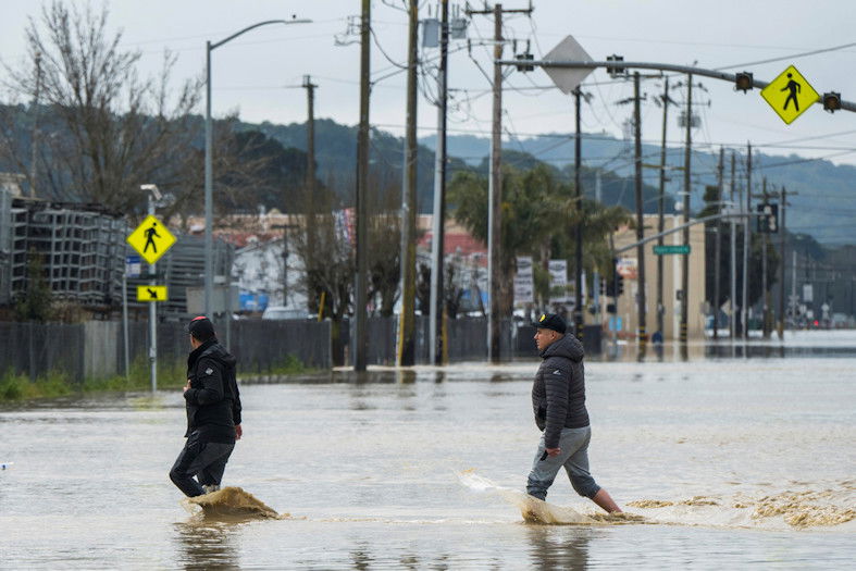 People walk through floodwaters in Watsonville, Calif., on Saturday