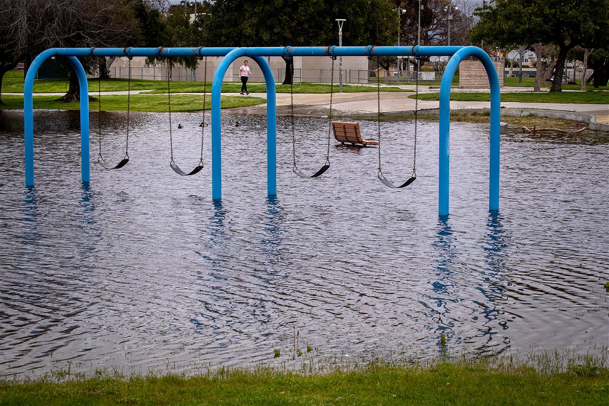 <i>Allen J. Schaben/Los Angeles Times/Getty Images</i><br/>A person walks past a flooded playground section in Huntington Beach Monday