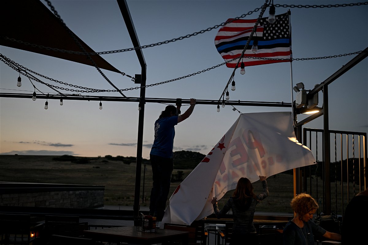 <i>AAron Ontiveroz/MediaNews Group/The Denver Post/Getty Images</i><br/>Brooke Wyatt and Michael Scileppi take down a Tina Peters banner after a watch party for her unsuccessful bid to win the Republican candidacy for secretary of state on June 28